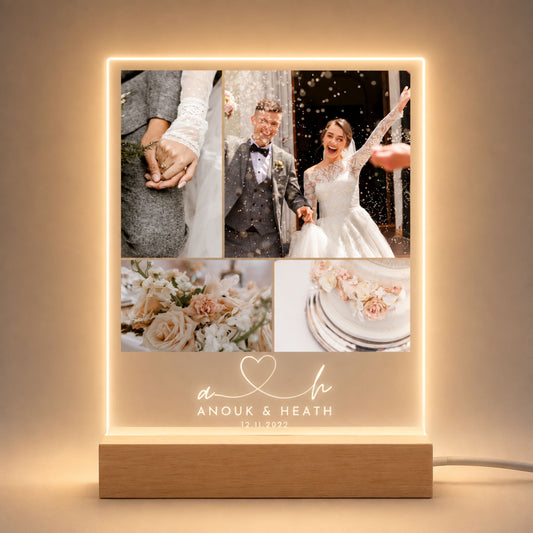 Studio front view of illuminated four-picture wedding collage acrylic plaque with script monogram initials glowing warm white on a natural wooden LED stand.