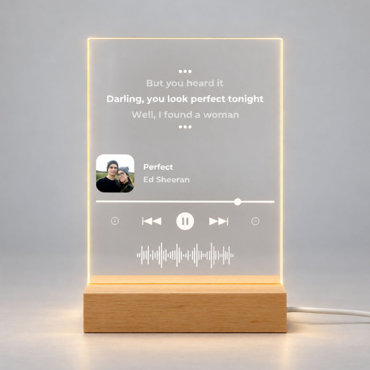 Studio front view of illuminated acrylic night light featuring custom song lyrics and small photo glowing warm white on a natural wooden LED stand.
