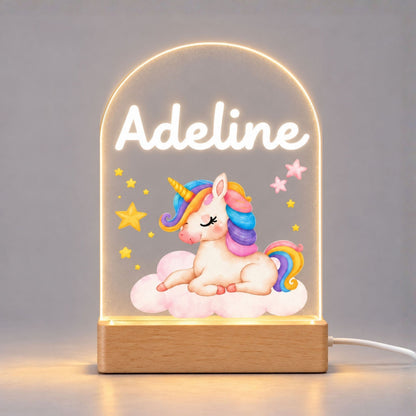 Illuminated baby unicorn acrylic night light on a plain light background, with a personalized name above the artwork and a wooden base.