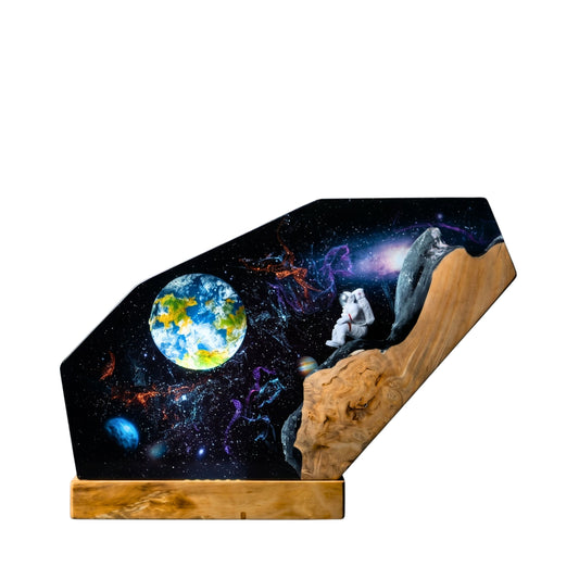 Handcrafted astronaut galaxy epoxy resin night light on a wooden base isolated on a clean white background, showcasing an intricate outer space scene with a miniature astronaut sitting on a wooden cliff.