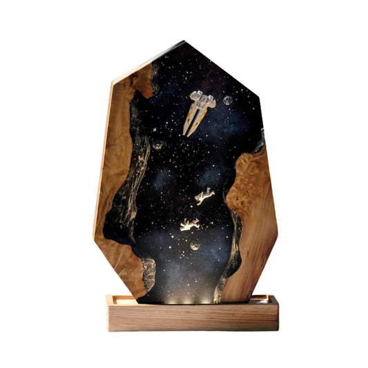 A handcrafted hexagonal resin lamp featuring a deep space scene with a spaceship and two astronauts drifting between two natural wood edges.
