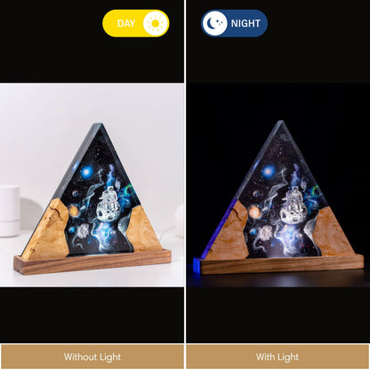 Split view of a triangular resin lamp showing the "Warm Light" effect in daylight versus the "Blue Light" glow in a dark room, highlighting the internal nebula and explorer details.