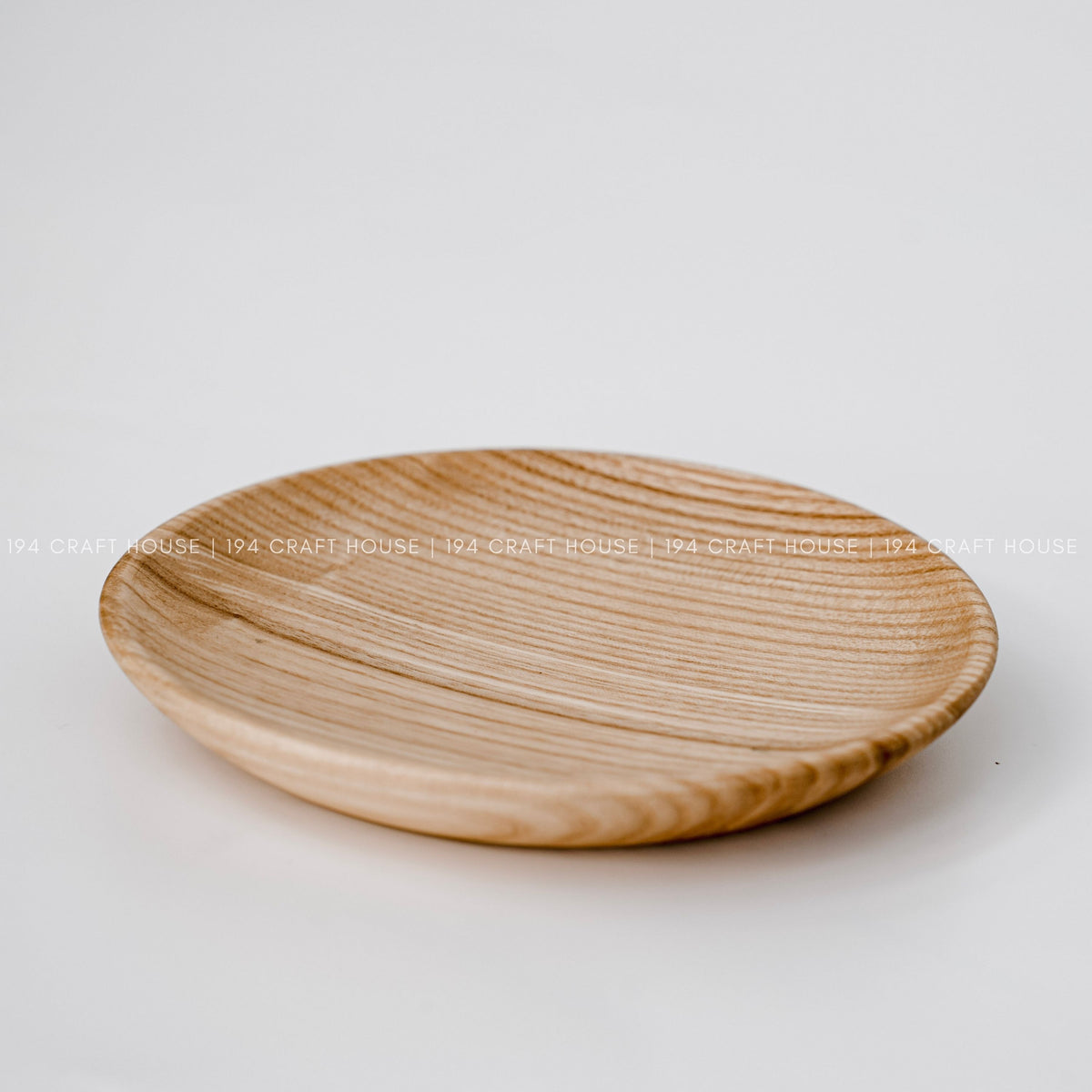 Angled view of a round wood plate showing its grain and raised edge