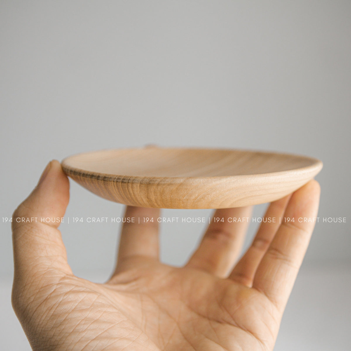 Side view of the shallow raised edge of a wood plate held in a hand