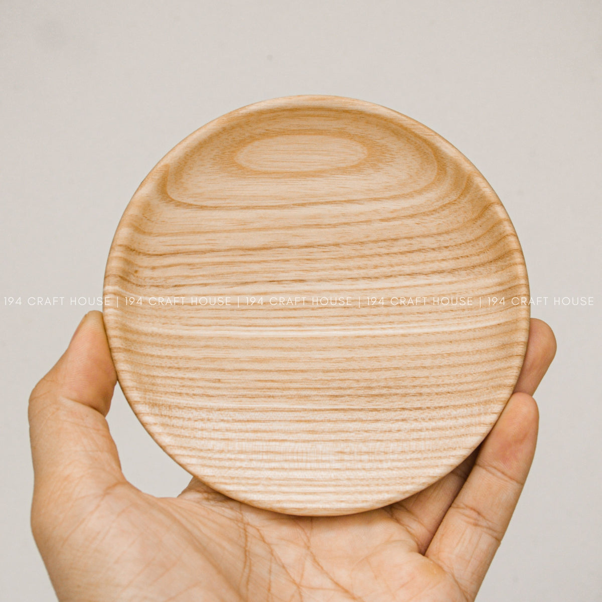 Round wood plate shown from above resting in a person's hand