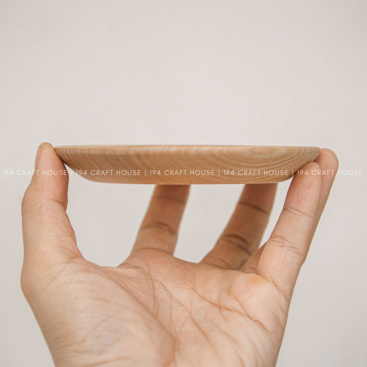 Thin side profile of a round wood plate supported by a hand