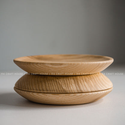Two round wood plates shown stacked in a side profile against a neutral background