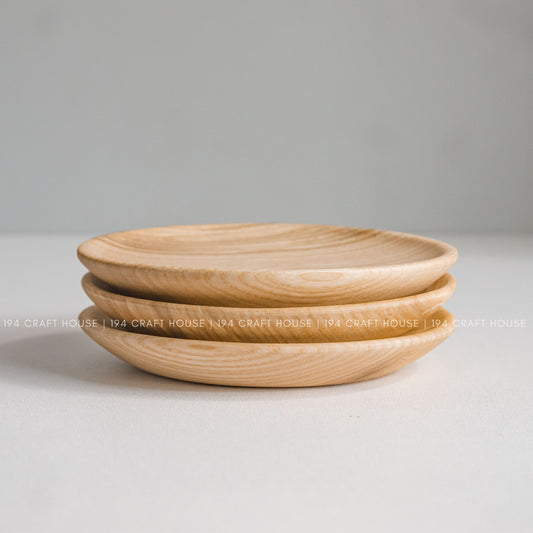 Two shallow round wood plates stacked together on a light surface