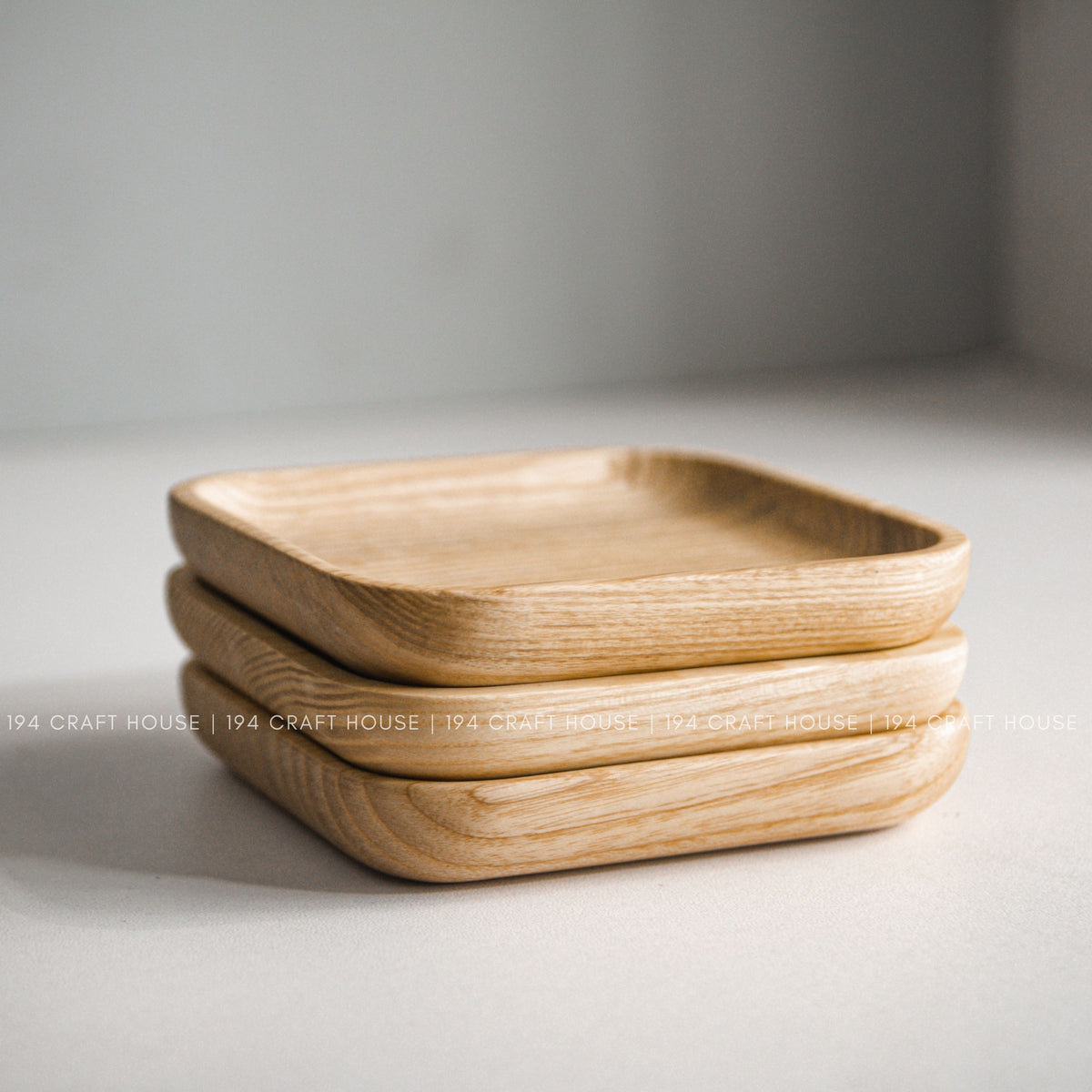 Several light wood square trays with rounded corners stacked together
