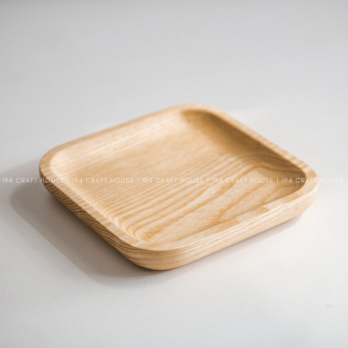 Light wood square tray with rounded corners and raised edges shown at an angle