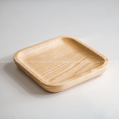 Light wood square tray with rounded corners and raised edges shown at an angle