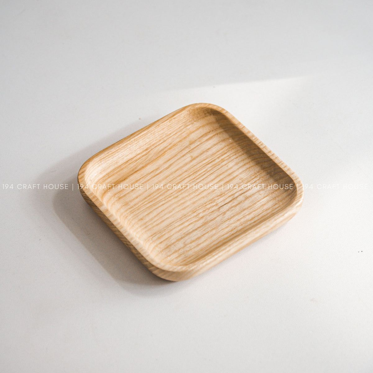 Light wood square tray with rounded corners photographed from above on a white surface
