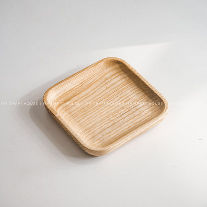 Light wood square tray with rounded corners photographed from above on a white surface