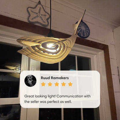 Illuminated whale pendant light hanging by a window with customer review overlay