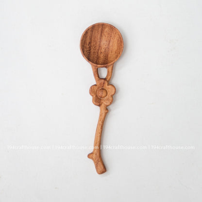 Front view of a handcrafted flower handle Doussie wood spice spoon on a clean white background.