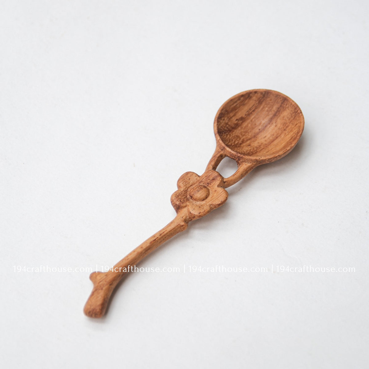 Side-angle product view of a Doussie wood mini spice spoon with carved flower handle and rounded scoop.