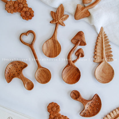 Collection of unique hand-carved wooden spoons with mushroom, leaf, heart, and nature-inspired designs